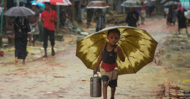 A Rohingya refugee boy shelters under an umbrella as he makes his way during monsoon rainfall at Kutupalong refugee camp in Ukhia, Cox's Bazar, Bangladesh, Sept. 12, 2019. (AFP Photo)