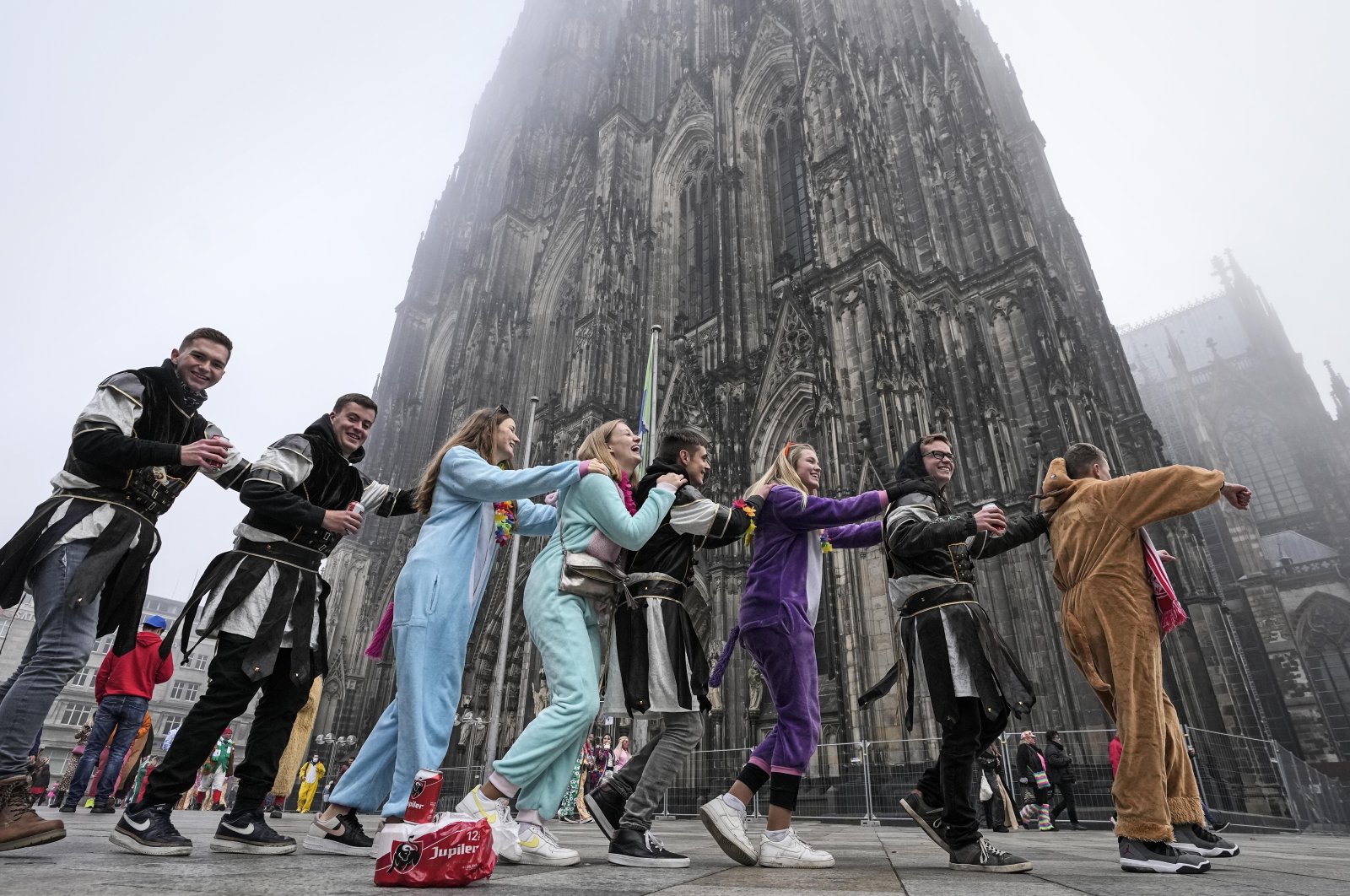 Young carnival revellers dance in front of the Cologne Cathedral when tens of thousands celebrate the start of the carnival season in the streets of Cologne, Germany, Nov. 11, 2021. (AP Photo)