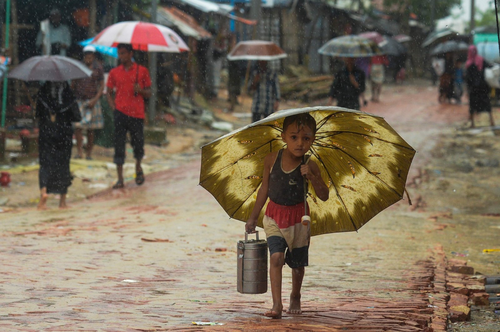 A Rohingya refugee boy shelters under an umbrella as he makes his way during monsoon rainfall at Kutupalong refugee camp in Ukhia, Cox's Bazar, Bangladesh, Sept. 12, 2019. (AFP Photo)