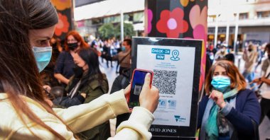 A customer scans a QR code to enter a department store in Melbourne as the city further lifts COVID-19 restrictions allowing nonessential retail shops to open and travel to the regions of Victoria after the city's sixth lockdown, Australia, Oct. 29, 2021. (AFP Photo)