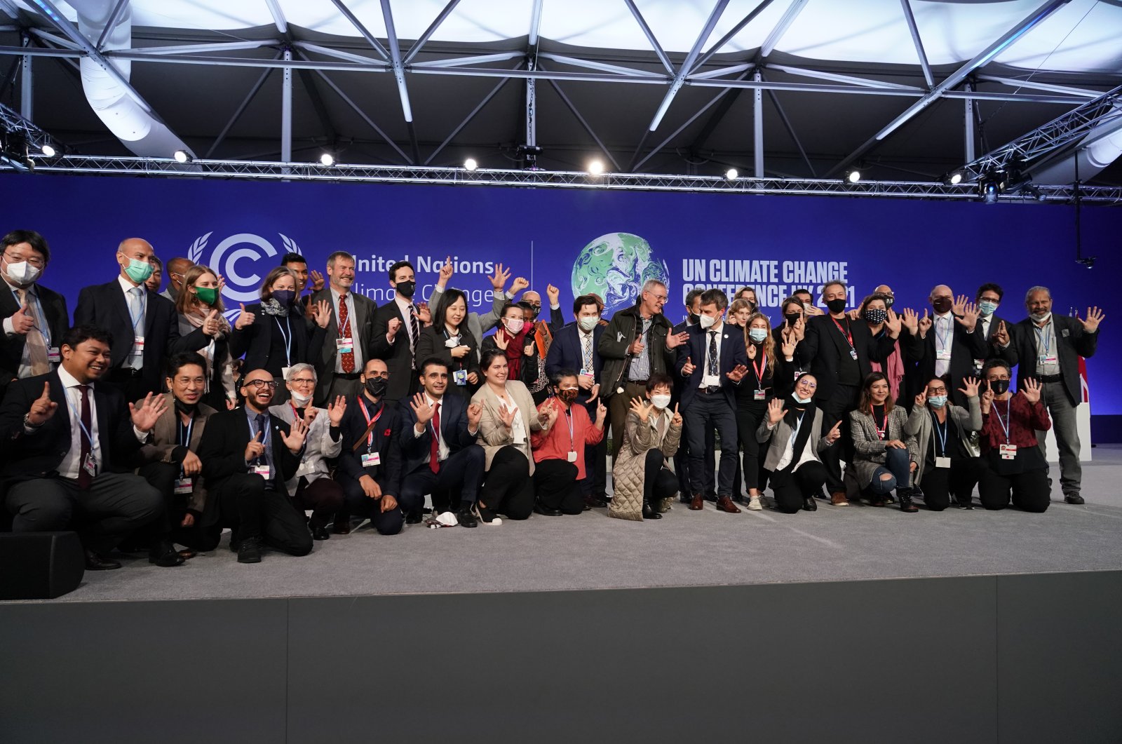 Delegates from different countries pose for a group photograph together on stage in the plenary room at the COP26 U.N. Climate Summit, in Glasgow, Scotland, Nov. 13, 2021. (AP Photo)