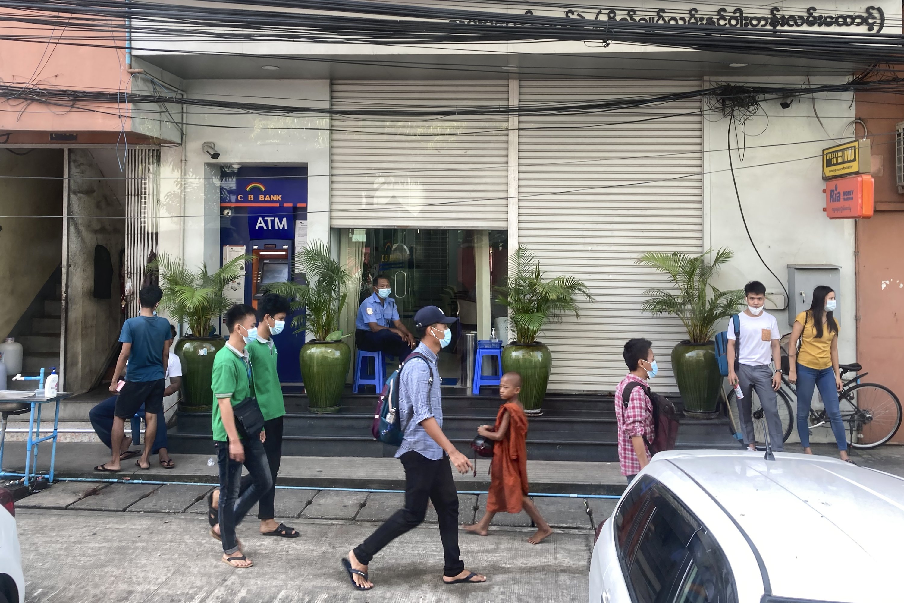 Orang-orang berjalan melewati bank dan mesin ATM di Yangon, Myanmar, 12 November 2021. (AP Photo)
