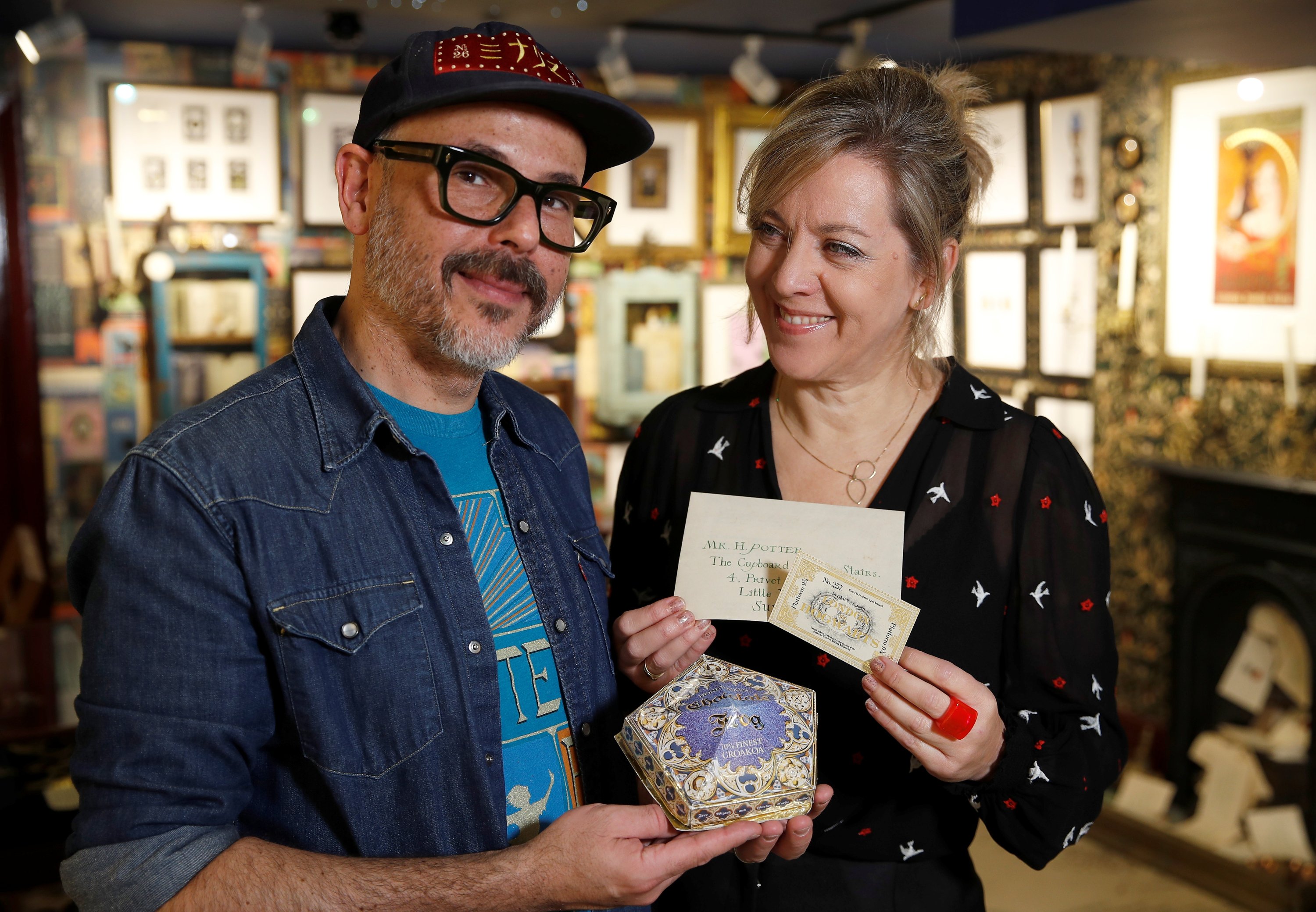 Artists Eduardo Lima and Miraphora Mina who created the graphic style of the Harry Potter movies, hold actual props they made for the movie, 'Harry Potter and the Philosopher's Stone,' at their store in London, Britain, Nov. 9, 2021. (REUTERS Photo)