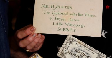 Artists Eduardo Lima and Miraphora Mina who created the graphic style of the Harry Potter movies, hold actual props they made for the movie, "Harry Potter and the Philosopher's Stone," at their store in London, Britain, Nov. 9, 2021. (REUTERS Photo)