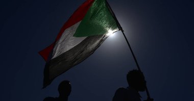 A man stands waving a Sudanese national flag as people protesting against the military coup in Sudan gather during a demonstration in the east of Khartoum, Sudan, Nov. 13, 2021. (Photo by AFP)