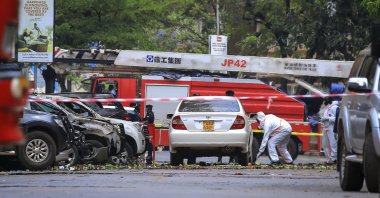 Security forces and forensics officers examine the scene of a blast on a street near the parliamentary building in Kampala, Uganda, Nov. 16, 2021. (AP Photo)