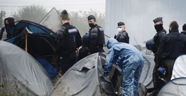 Police forces open tents as migrants are evacuated from a camp in Grande-Synthe, Northern France, Nov. 16, 2021. (AP Photo)