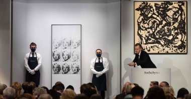 Sotheby's auctioneer Oliver Barker leads an auction of "The Macklowe Collection," alongside Andy Warhol's "Nine Marilyns" (L) sold for $47,373,000 and Jackson Pollock's "Number 17, 1951" (R), at Sotheby's in New York City, U.S., Nov. 15, 2021. (AFP Photo)
