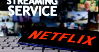 A smartphone with the Netflix logo is seen on a keyboard in front of a display that reads "Streaming service," March 24, 2020. (Reuters Photo)