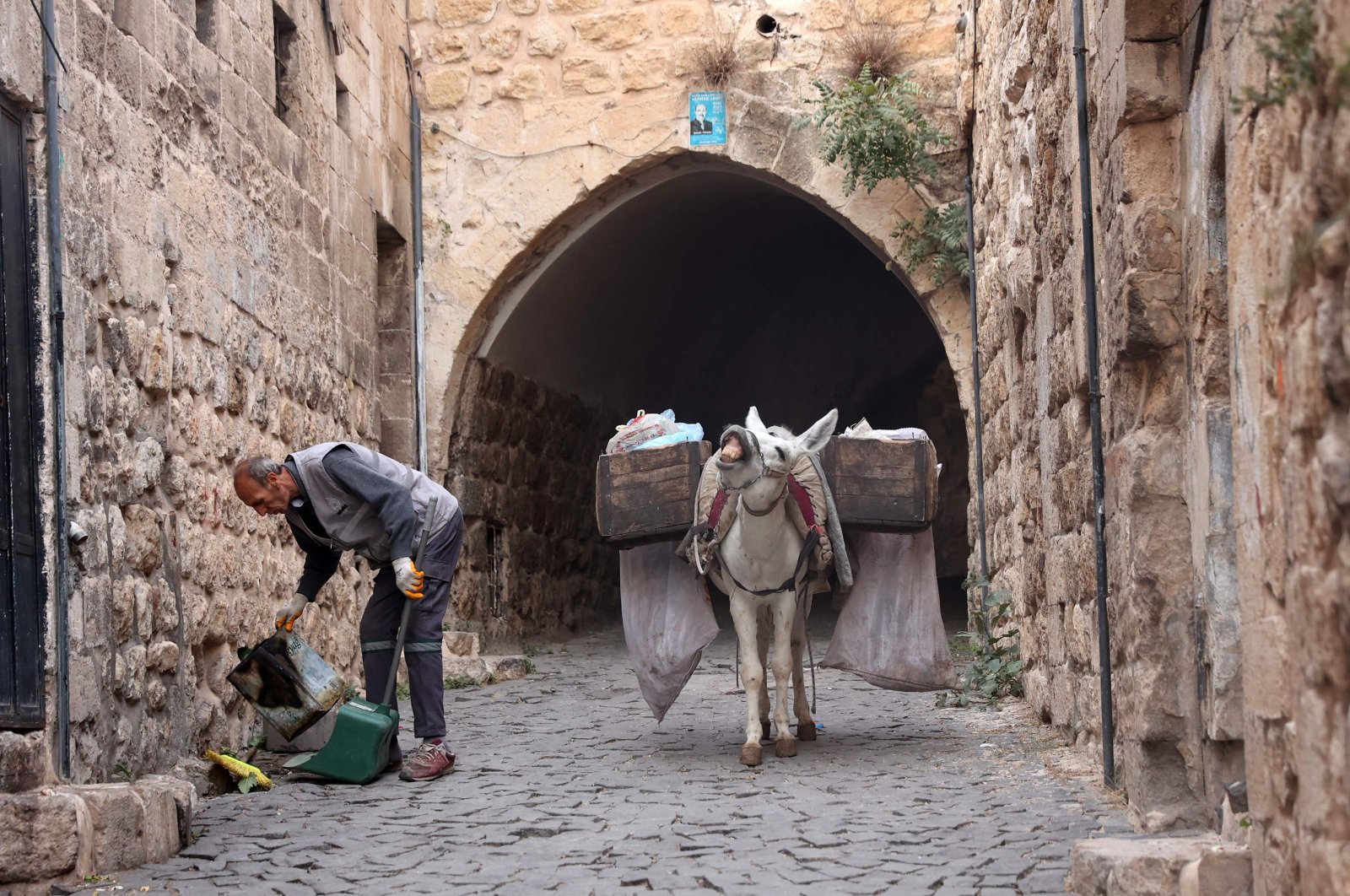 A municipal employee guiding a donkey collects garbage in the old city of Mardin, southeastern Turkey, on Oct. 18, 2021. (AFP Photo)