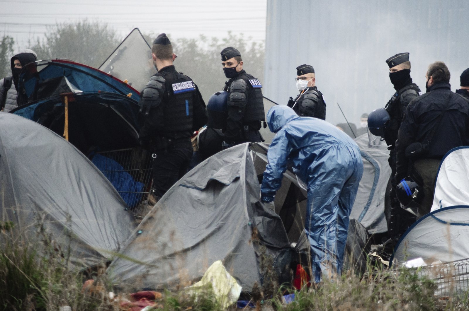 Police forces open tents as migrants are evacuated from a camp in Grande-Synthe, Northern France, Nov. 16, 2021. (AP Photo)