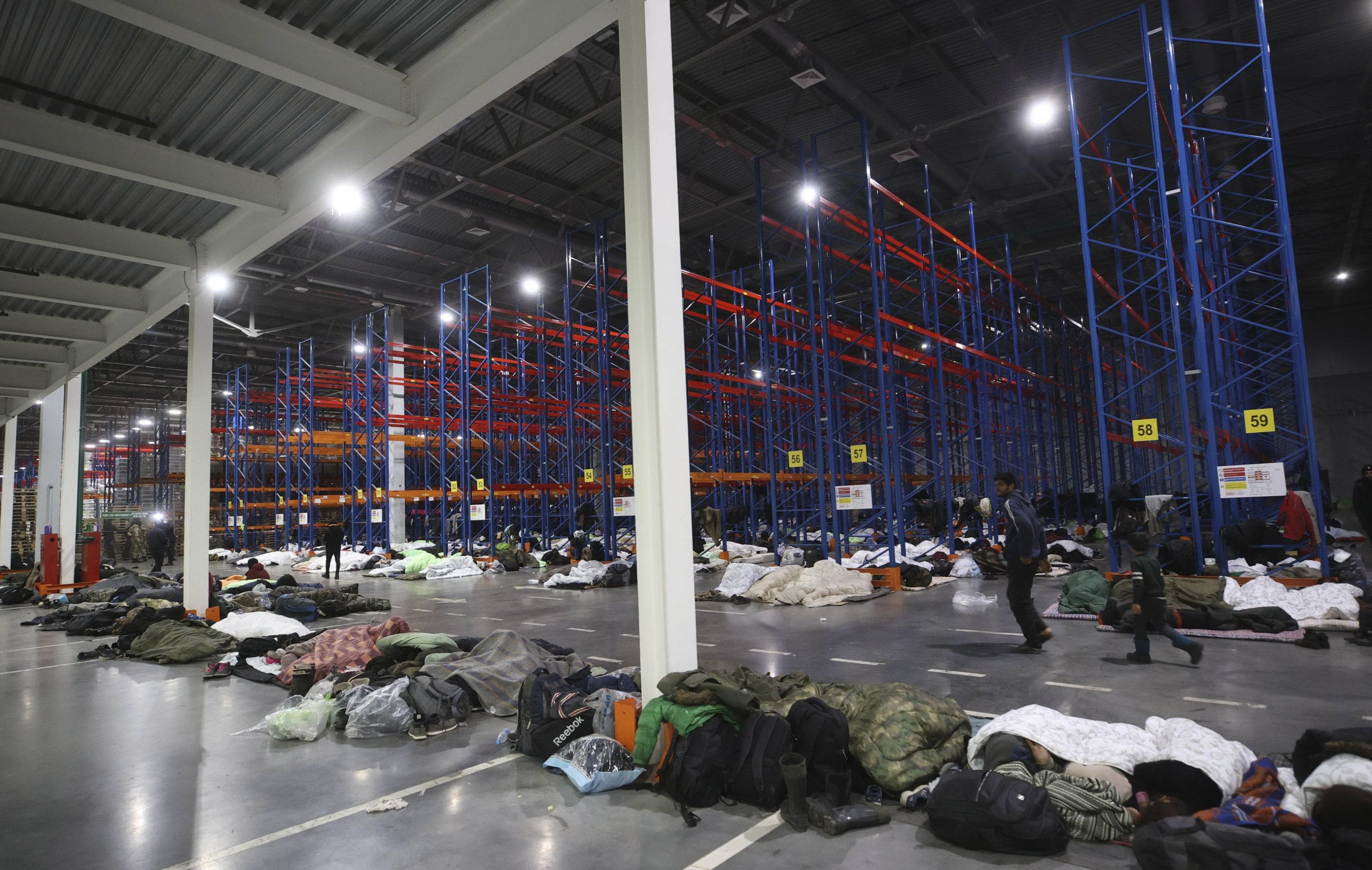Migrants settle in a logistics center in the checkpoint "Kuznitsa" at the Belarus-Poland border near Grodno, Belarus, Nov. 17, 2021. (AP Photo)