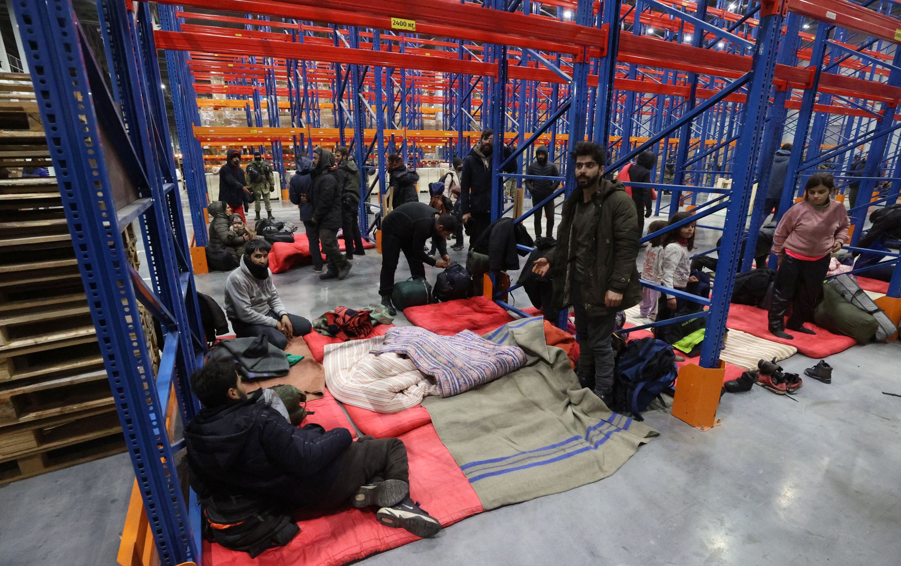 People preparing to spend the night at the logistics center "Bruzgi" at the Belarusian-Polish border at the Bruzgi-Kuznica checkpoint in the Grodno region, Belarus, Nov. 16 2021. (BelTA Handout Photo via EPA-EFE)