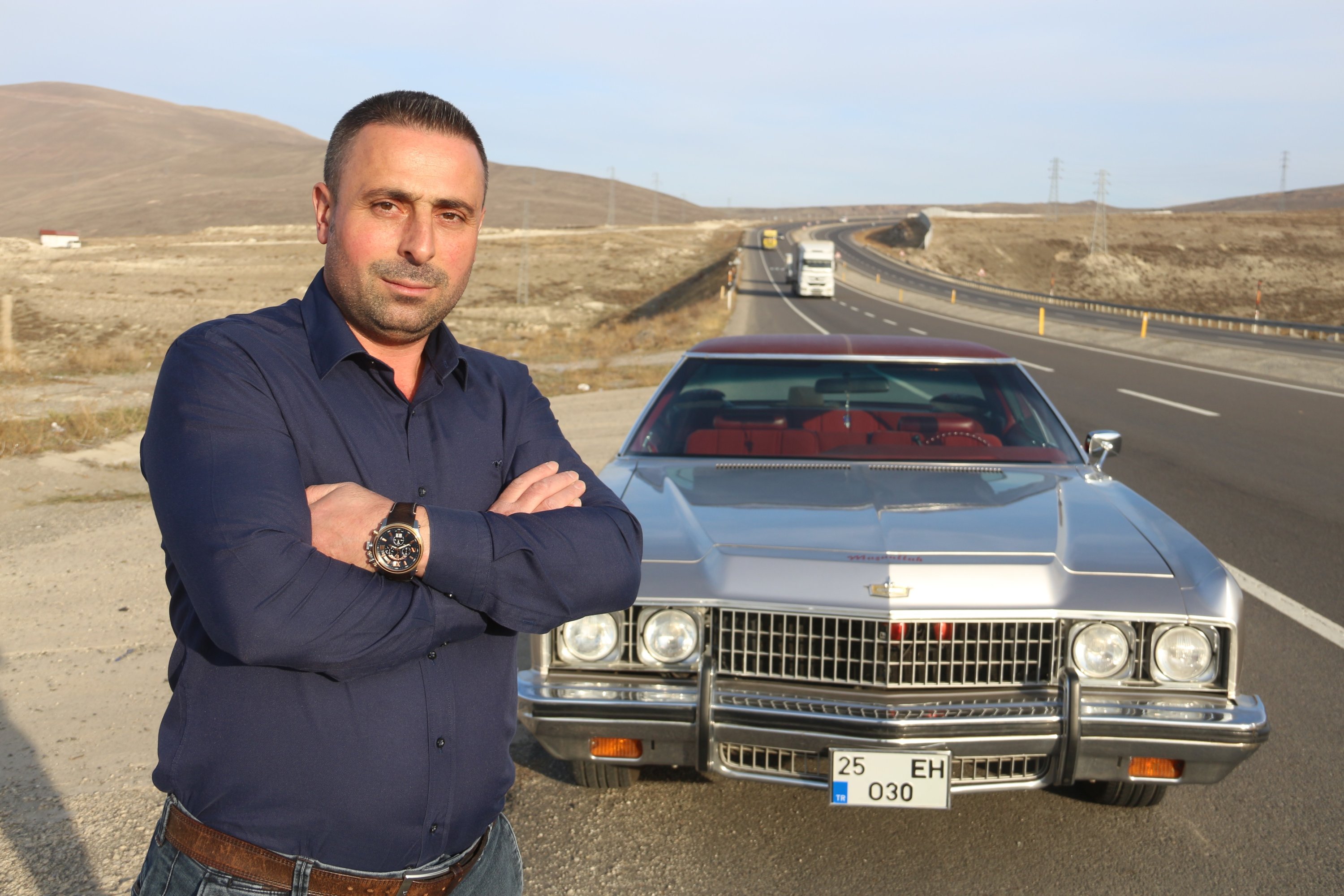 Haluk Ertek standing in front of his 1973 Chevrolet Caprice Classic in Erzurum, Turkey, Nov. 9, 2021 (IHA Photo)