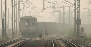 A woman crosses railway tracks as a goods train passes by, on a smoggy day in New Delhi, India, Nov. 12, 2021. (Reuters Photo)