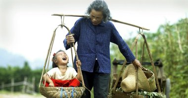 A grandmother carries her laughing granddaughter outside the tourist mecca of Yangshou in southern China, Oct. 1, 2003 . (AFP Photo)