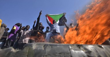 A man holds a Sudanese national near a blaze as people protest against the military coup in Khartoum, Sudan, Nov. 13, 2021. (AFP Photo)
