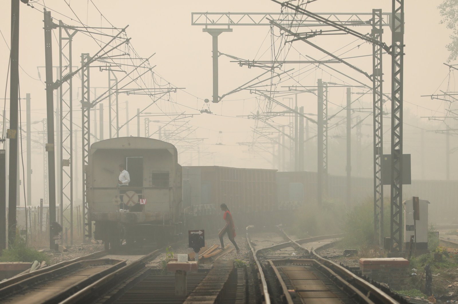 A woman crosses railway tracks as a goods train passes by, on a smoggy day in New Delhi, India, Nov. 12, 2021. (Reuters Photo)