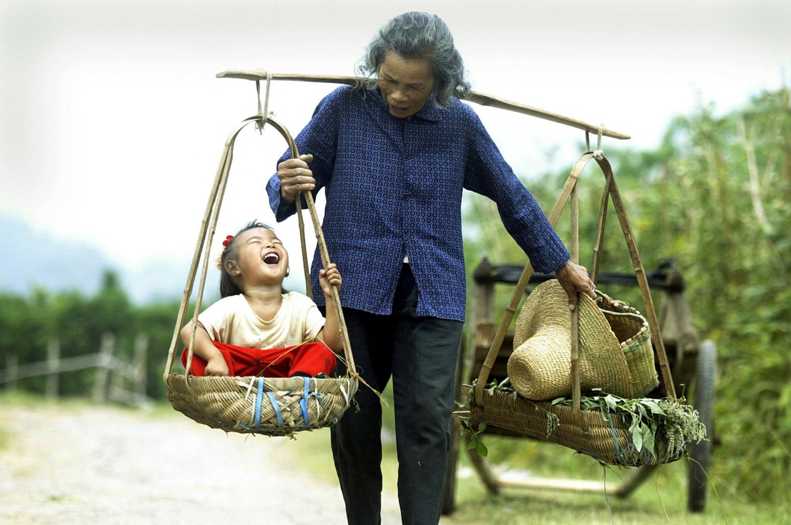 A grandmother carries her laughing granddaughter outside the tourist mecca of Yangshou in southern China, Oct. 1, 2003 . (AFP Photo)