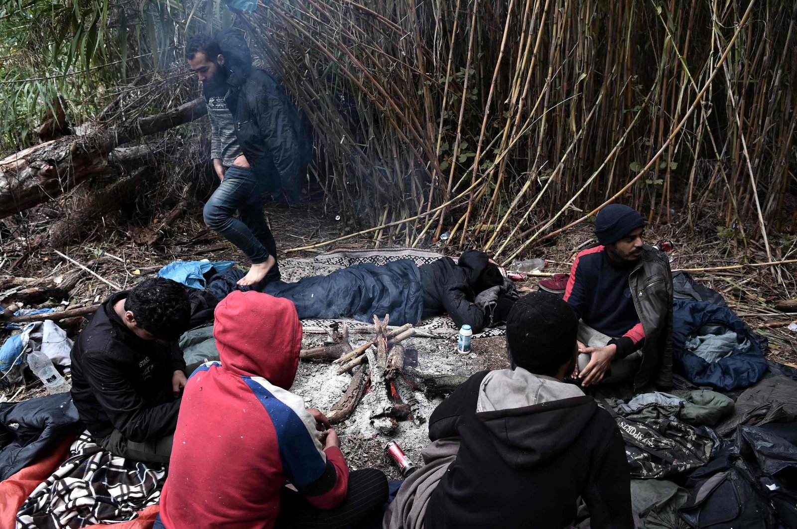 Migrants try to warm themselves by a fire near Idomeni at the border between Greece and North Macedonia on October 18, 2021. (AFP Photo)