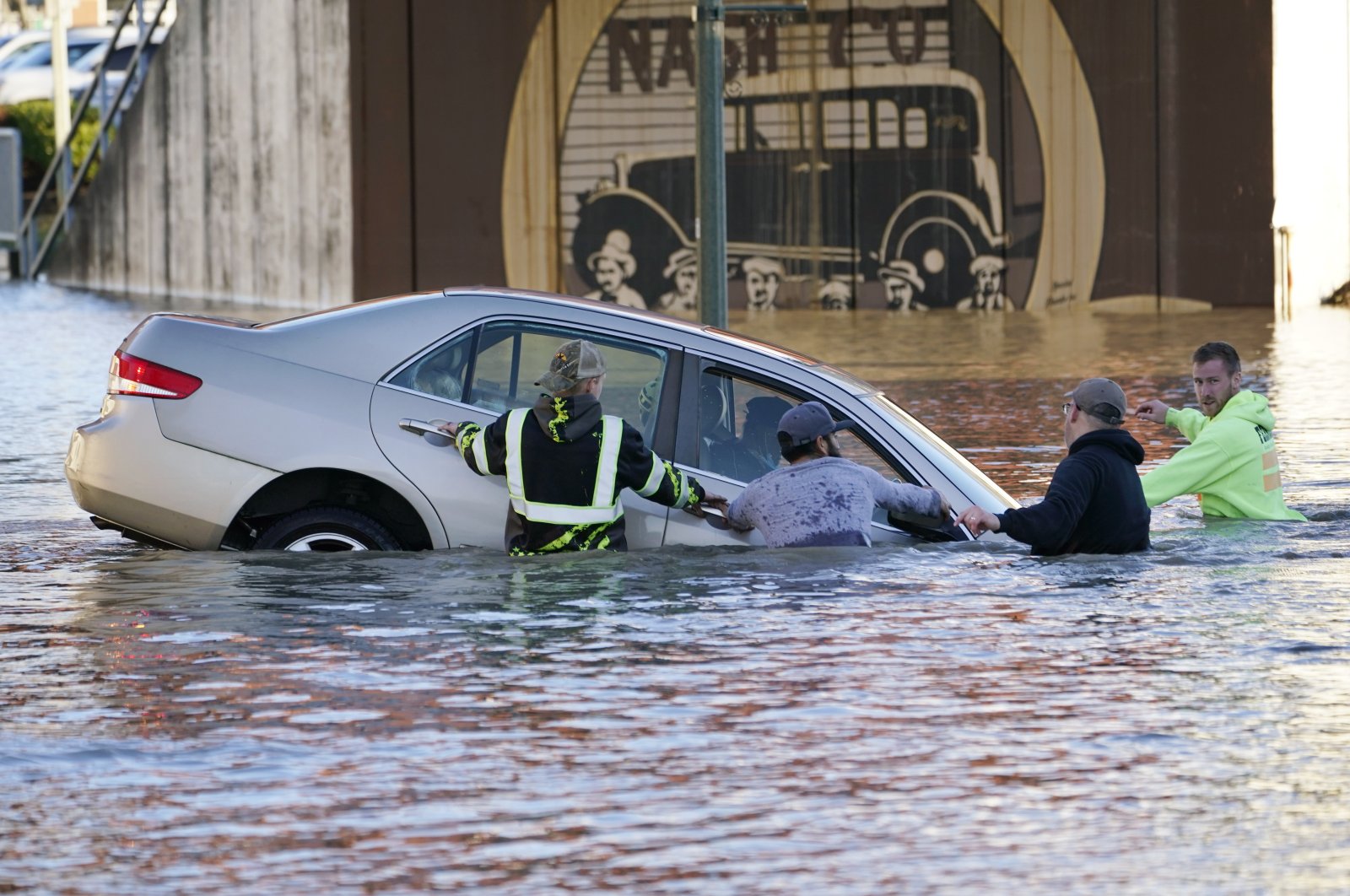 Passersby surround a car whose driver went past a barricade and into the flooded Nooksack River in Ferndale, Washington, U.S., Nov. 16, 2021. (AP Photo)