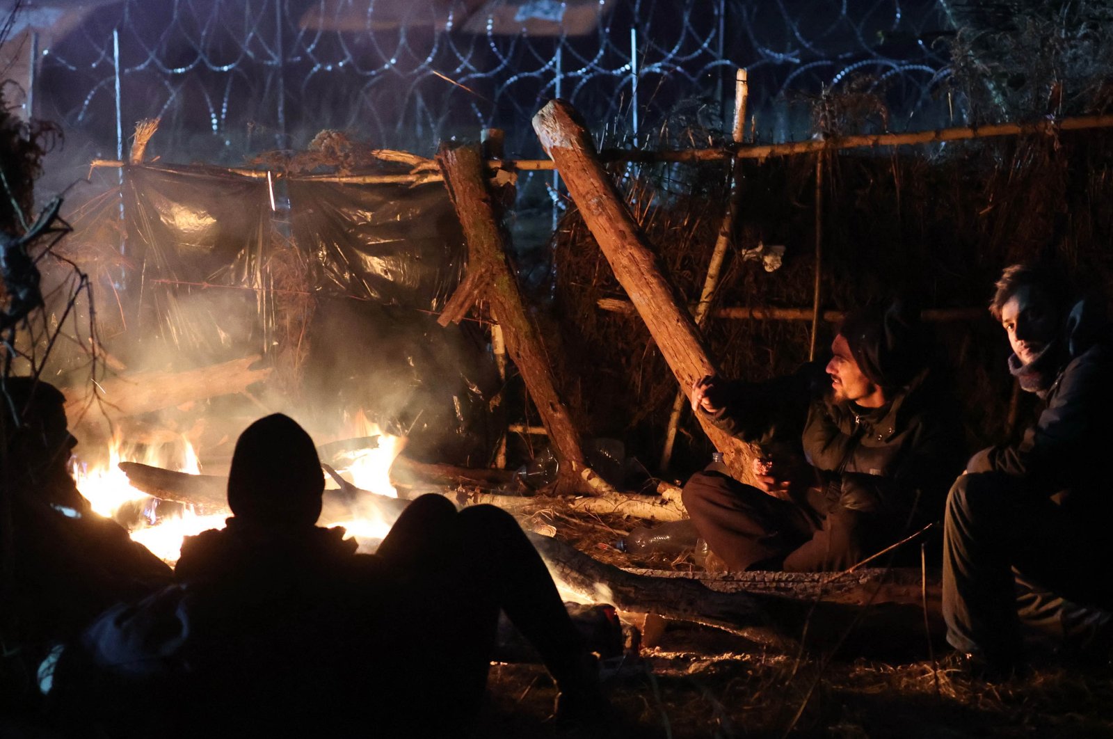 Migrants aiming to cross into Poland warm themselves by a fire on the Belarusian-Polish border in the Grodno region, Belarus, Nov. 16, 2021. (AFP Photo)