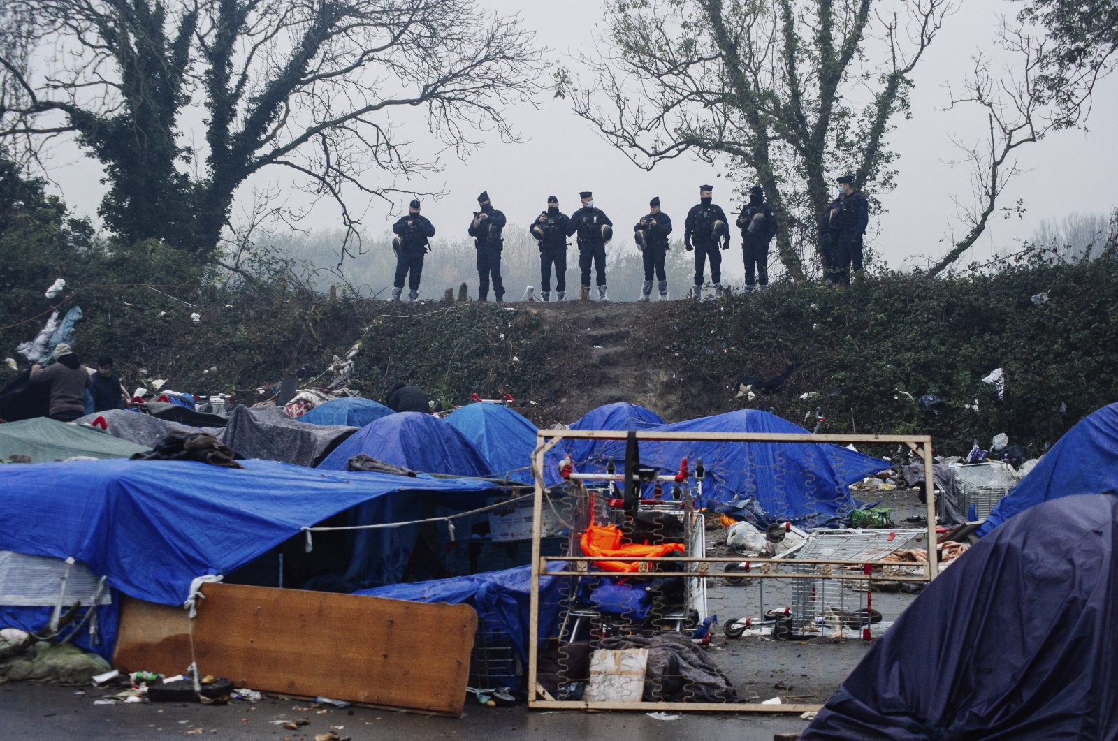 Police forces watch a makeshift migrant camp in Grande-Synthe, Northern France, Nov. 16, 2021. (AP File Photo)