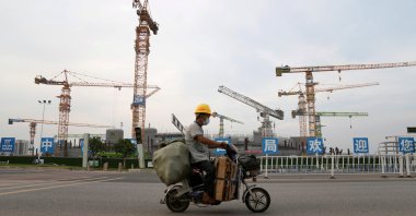A man rides an electric bicycle past the construction site of Guangzhou Evergrande Soccer Stadium, a new stadium for Guangzhou FC developed by China Evergrande Group, Guangdong province, China, Sept. 26, 2021. (Reuters Photo)