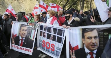 Georgian opposition protestors with its national flag and posters of ex-President Mikheil Saakashvili rally in his support in Tbilisi, Georgia, Nov. 15, 2021. (AP Photo)