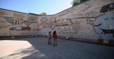Visitors gaze upon the largest mosaic in the world, placed on a large wall in Madaba, southwest of capital Amman, Jordan, Nov. 17, 2021. (AA Photo)