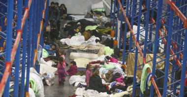Migrants settle for the night in the logistics center in the checkpoint "Kuznitsa" at the Belarus-Poland border near Grodno, Belarus, Nov. 18, 2021. (AP Photo)