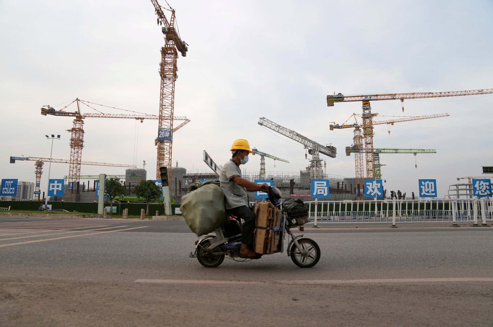 A man rides an electric bicycle past the construction site of Guangzhou Evergrande Soccer Stadium, a new stadium for Guangzhou FC developed by China Evergrande Group, Guangdong province, China, Sept. 26, 2021. (Reuters Photo)