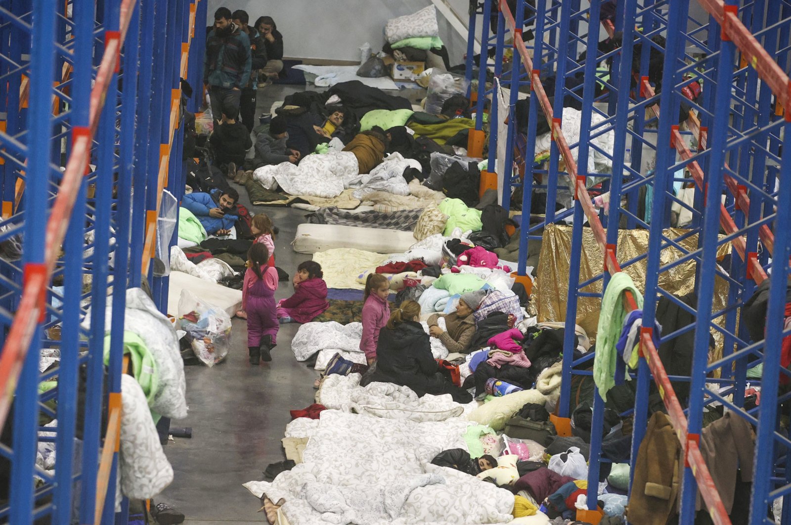 Migrants settle for the night in the logistics center in the checkpoint "Kuznitsa" at the Belarus-Poland border near Grodno, Belarus, Nov. 18, 2021. (AP Photo)