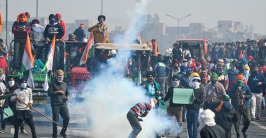 A farmer throws back a tear gas shell fired by the police to disperse them during a tractor rally as farmers continue to demonstrate against the central government's agricultural reforms in New Delhi, India, Jan. 26, 2021. (AFP Photo)