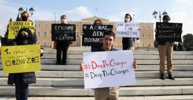 Sean Binder holds a placard during a demonstration by Amnesty International activists in solidarity with aid workers on trial over refugee rescues, outside the parliament building, in Athens, Greece, Nov. 15, 2021. (Reuters Photo)