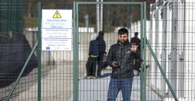 A migrant stands behind a gate at the newly built camp that was inaugurated by the European Union and International Organization for Migration officials along with Bosnian authorities near Bihac, northwestern Bosnia-Herzegovina, Nov. 19, 2021. (AP Photo)