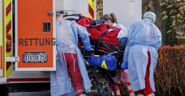 Rescue workers load a COVID-19 intensive care patient from an air rescue helicopter onto an ambulance vehicle at a sports field in Herrsching, Germany, Nov. 19, 2021. (dpa via AP)