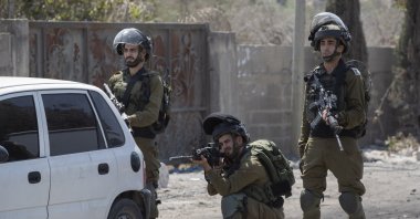 An Israeli soldier aims his weapon at Palestinians protesting against the creation of a new road for Israeli settlers, near the Palestinian village of Beita, north of the city of Nablus, the occupied West Bank, Palestine, Aug. 25, 2021. (AP File Photo)