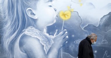 A pedestrian wearing a face mask to protect against coronavirus, walks in front of a mural, at a metro station in Athens, Greece, Nov. 15, 2021. (AP Photo)