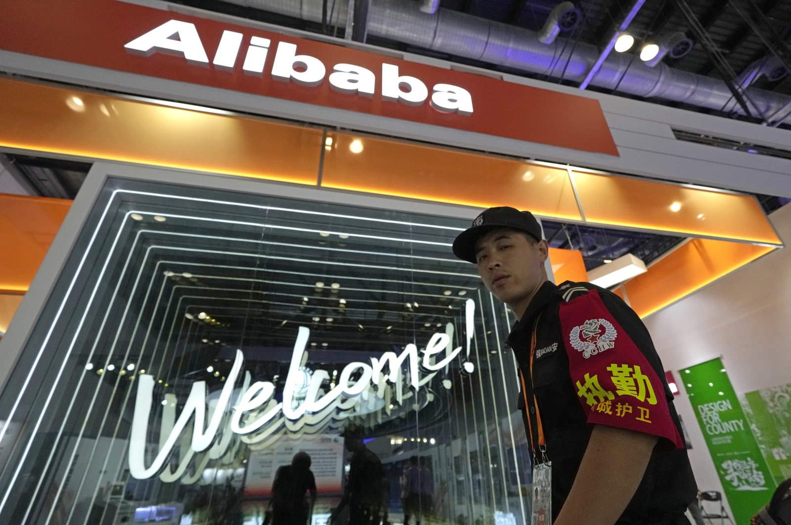 A security guard passes by the Alibaba booth at a trade show in Beijing, China, Sept. 7, 2021. (AP Photo)