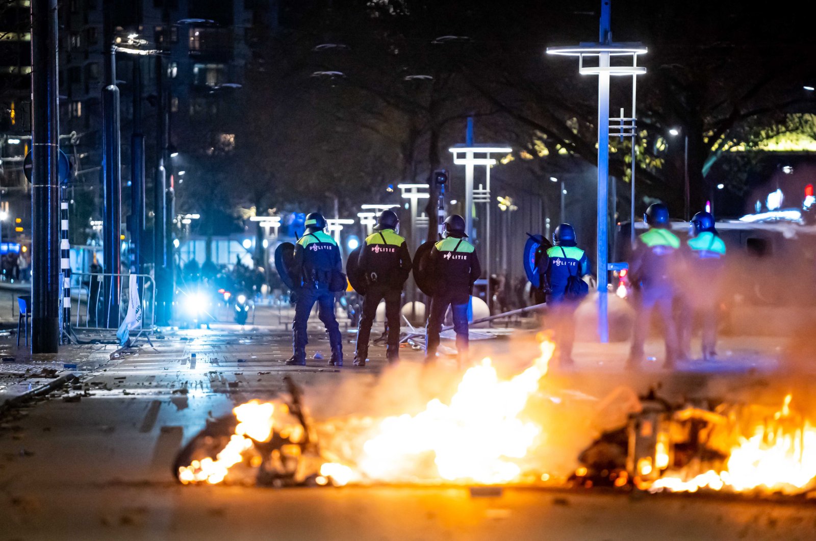 Police stand near burning objects after a protest against the &#039;2G policy&#039; turned into riots, with protesters setting fires in the street and destroying police cars and street furniture, Rotterdam, Netherlands, Nov. 19, 2021. (EPA Photo)