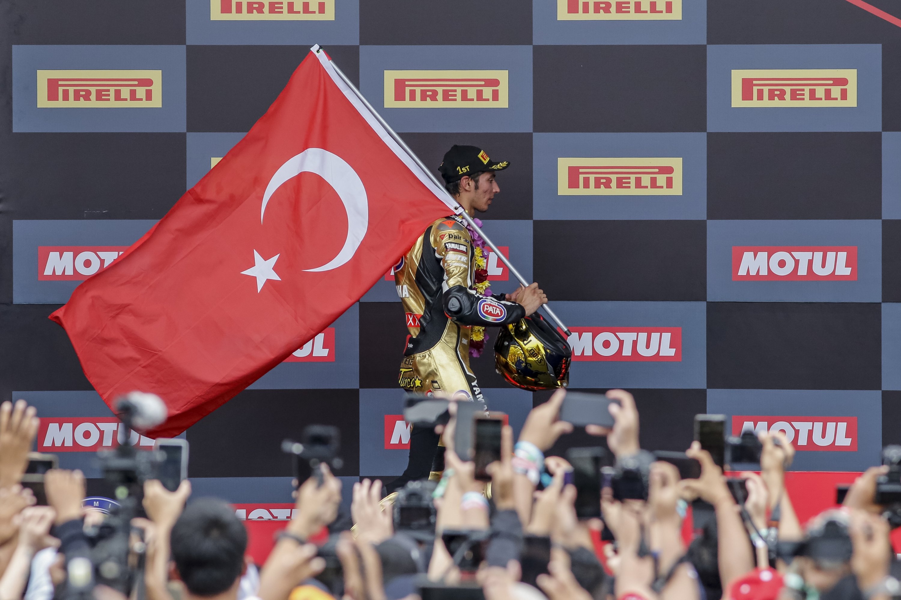 Toprak Razgatlıoğlu goes up on the stage holding a Turkish flag following the race, Lombok, Indonesia, Nov. 21, 2021 (DHA Photo)