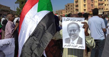 A Sudanese anti-coup protester holds a placard depicting ousted Prime Minister Abdalla Hamdok, who is under house arrest, and reading "legitimate prime minister" amid ongoing protests against last month&#039;s widely condemned military takeover in the "Street 40" of the capital&#039;s twin city of Umdurman, Sudan, Nov. 17, 2021. (AFP Photo)