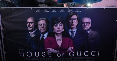 A bystander waves behind a backdrop ahead of the premiere of the film &quot;House of Gucci,&quot; in Milan, Italy, Nov. 13, 2021. (AFP Photo)