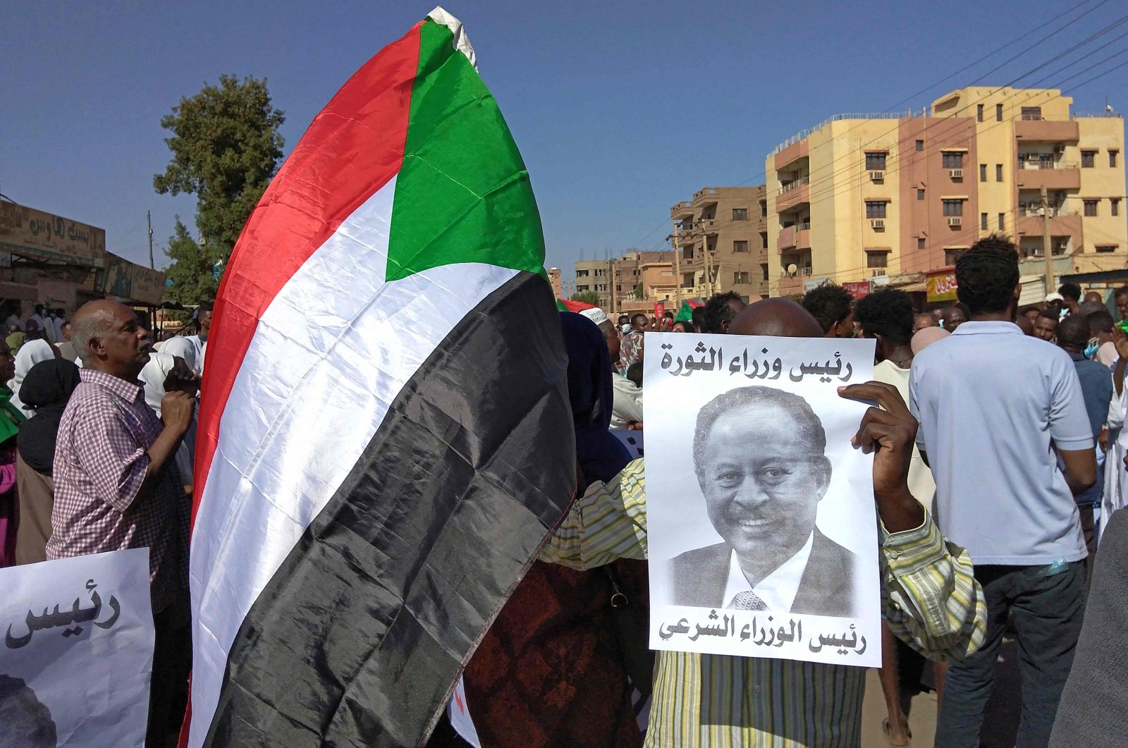 A Sudanese anti-coup protester holds a placard depicting ousted Prime Minister Abdalla Hamdok, who is under house arrest, and reading "legitimate prime minister" amid ongoing protests against last month&#039;s widely condemned military takeover in the "Street 40" of the capital&#039;s twin city of Umdurman, Sudan, Nov. 17, 2021. (AFP Photo)