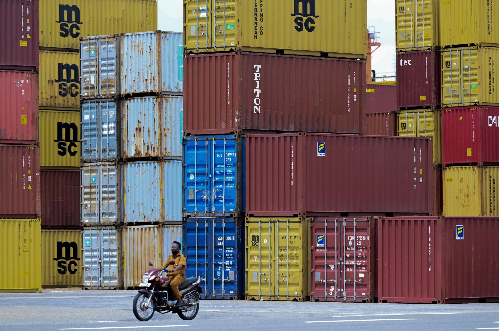 A motorcyclist rides past containers at the East Terminal operated part of the Colombo port, Sri Lanka, June 4, 2021. (AFP Photo)