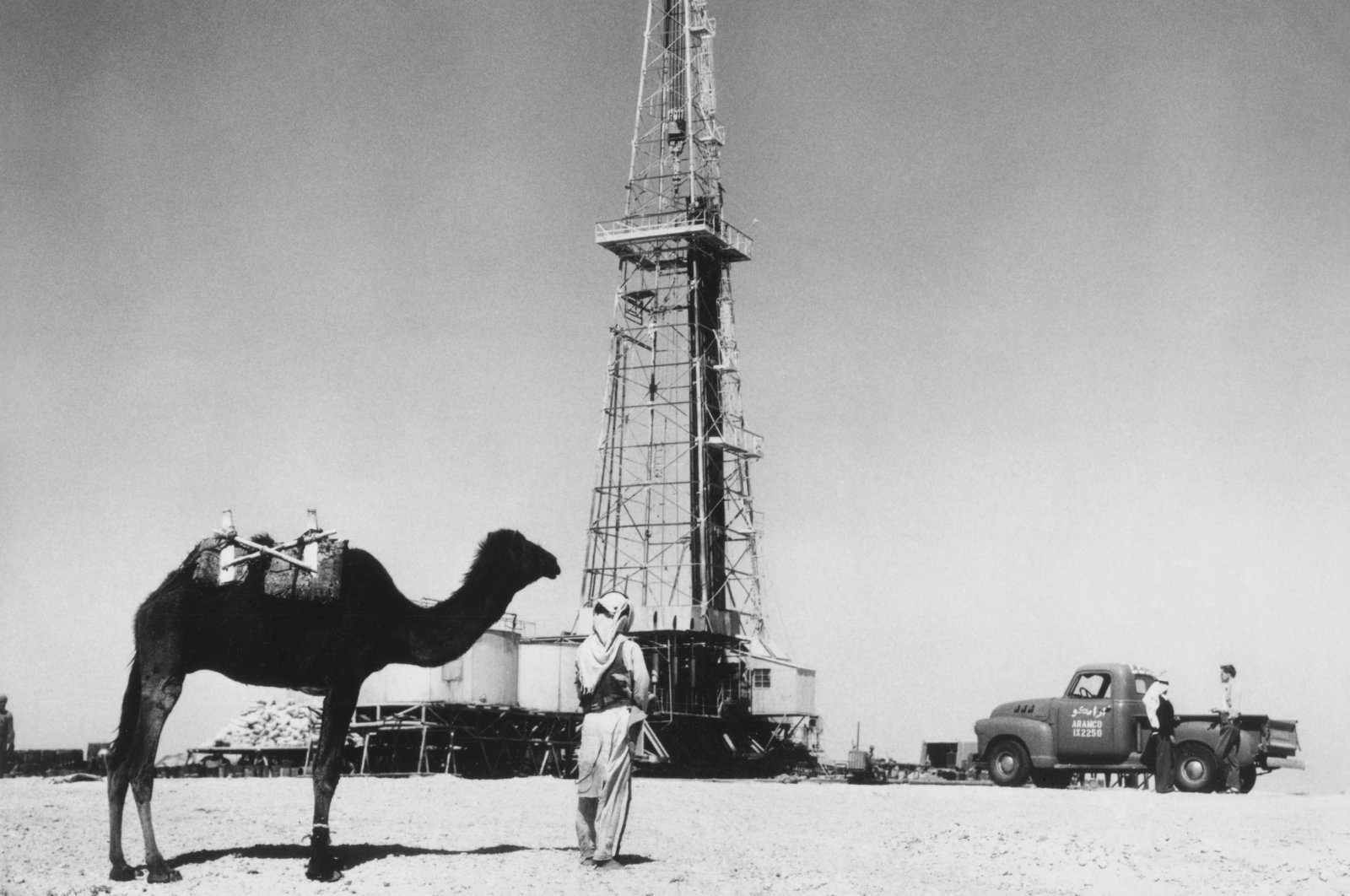 A man with his camel can be seen near an oil well in Saudi Arabia in the 1940s. (Getty Images)