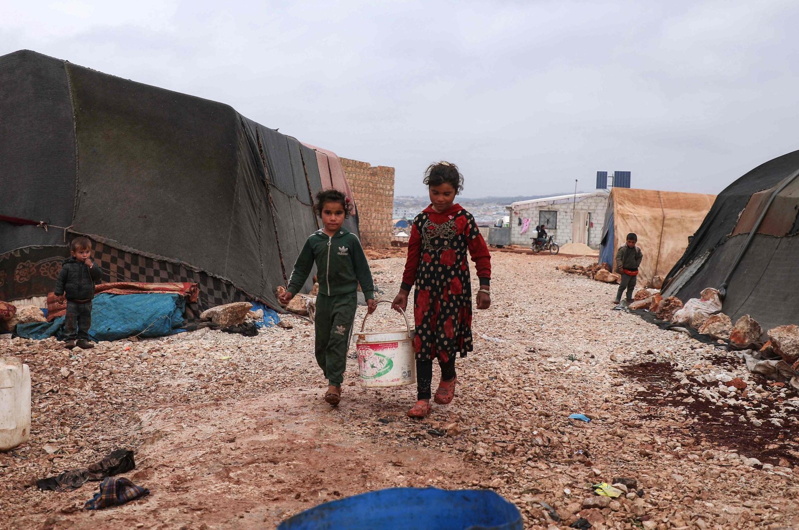 On the occasion of International Day for Children&#039;s Rights, children are seen carrying a bucket of water in the Bardaqli camp for displaced people in the town of Dana as winter approaches, Idlib province, northwestern Syria, Nov. 20, 2021 (AFP Photo)