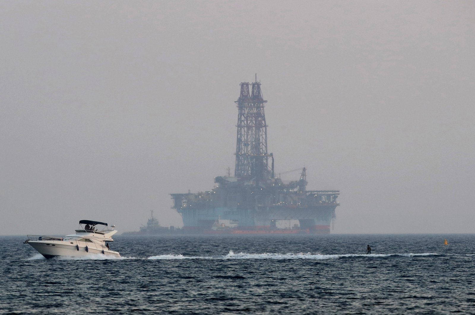 An offshore drilling rig is seen off Cyprus&#039; coastal city of Limasol as a boat passes with a skier. (AP File Photo)