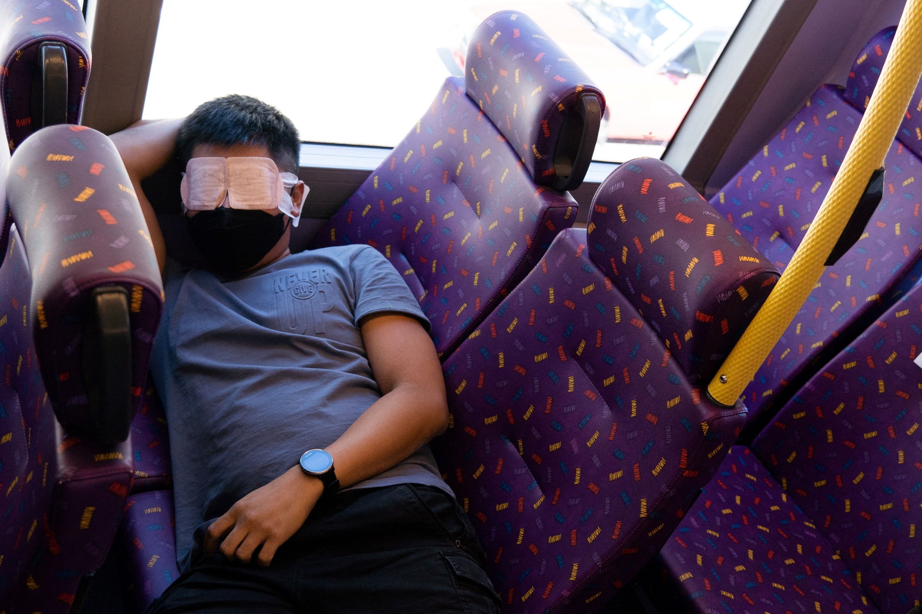 A passenger sleeps on a bus operated by a Hong Kong travel agency offering a five-hour "quiet bus" tour marketed as a "route to nowhere" for travel-craving and restless residents to snooze on board in Hong Kong, Nov. 14, 2021. (AFP Photo)